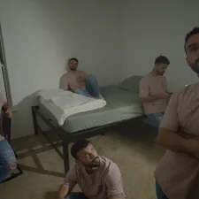 a group of men sitting around a bed in a room related to Exploring the Lives of Jewish Men at Home