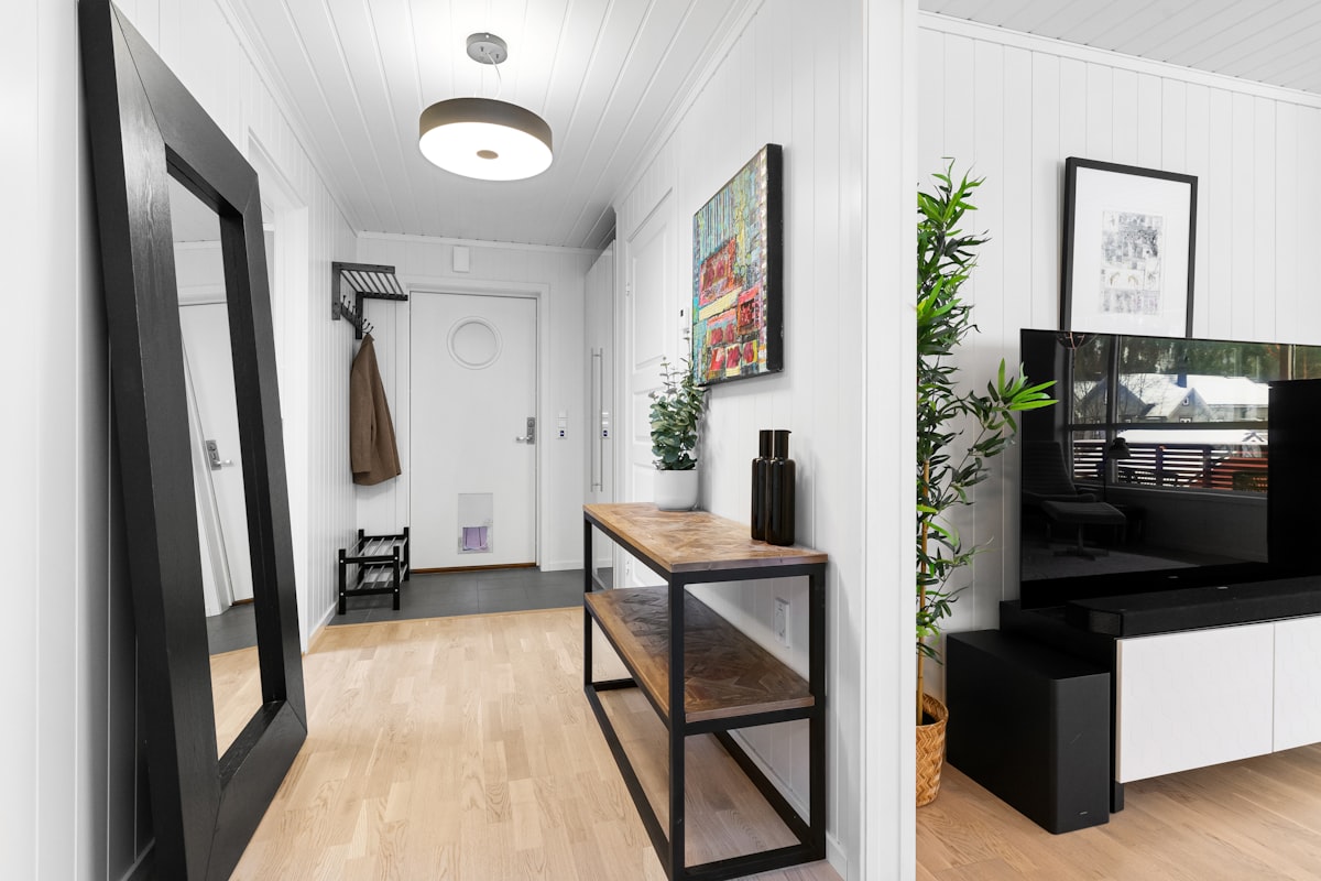 A hallway with a mirror and a television on a stand related to Elevate Your Home's First Impression: Entryway Hall Tree with Storage