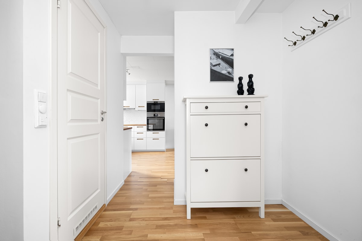 A hallway with a white cabinet and wooden floors related to Narrow Shoe Cabinet Entryway Ideas to Enhance Your Home