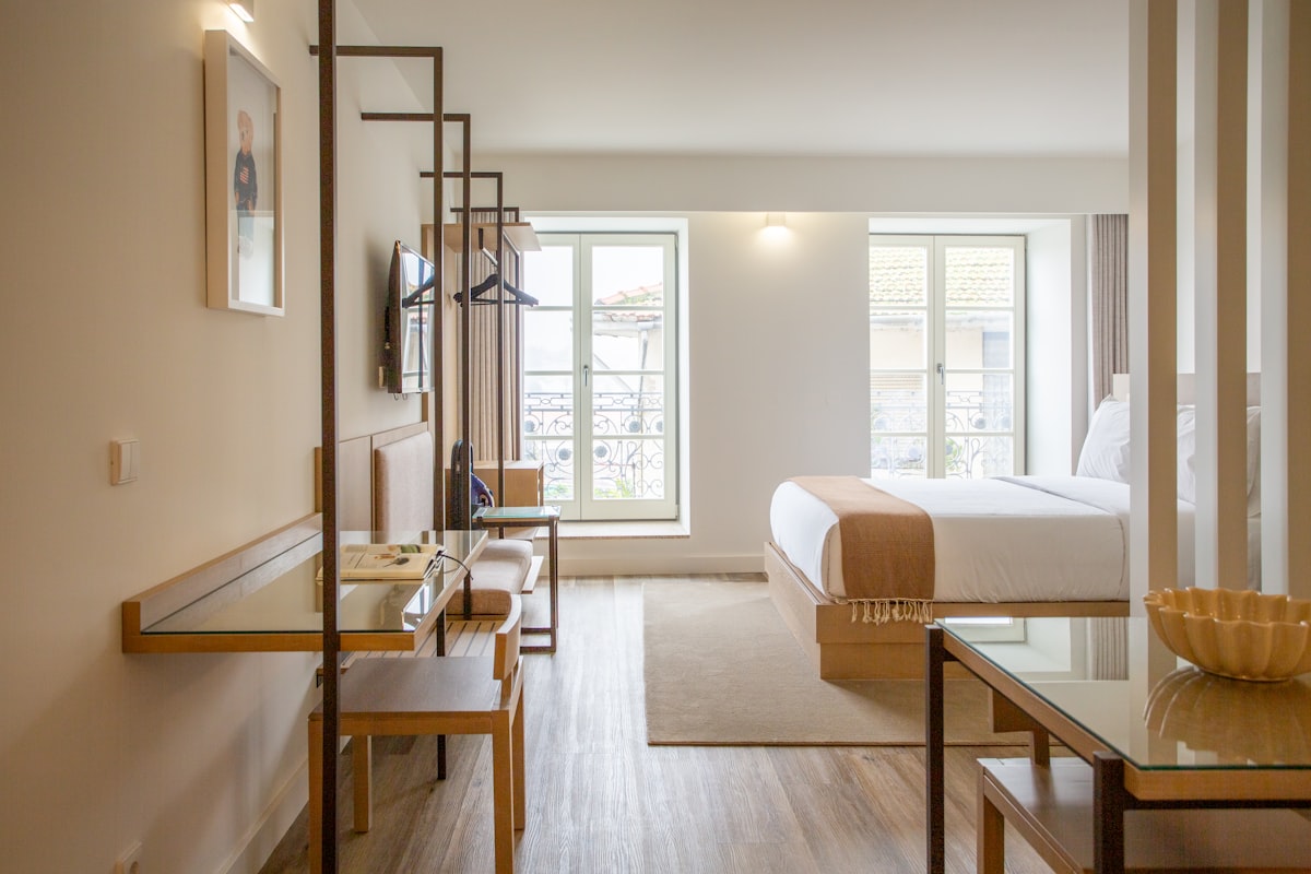 a hotel room with a bed, desk, chairs and a television related to Sleep Soundly in Style: The Best Bed for Your Studio Apartment