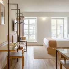 a hotel room with a bed, desk, chairs and a television related to Sleep Soundly in Style: The Best Bed for Your Studio Apartment