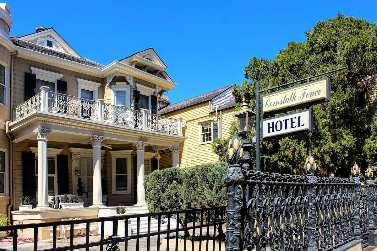 a hotel sign is posted on a wrought iron fence related to Exploring New Orleans: The Charm of Bed and Breakfasts in the French Quarter