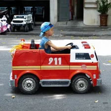 A kid riding around in a toy firetruck on the streets of Hanoi. related to Transform Your Toddler's Room with a Step 2 Firetruck Bed