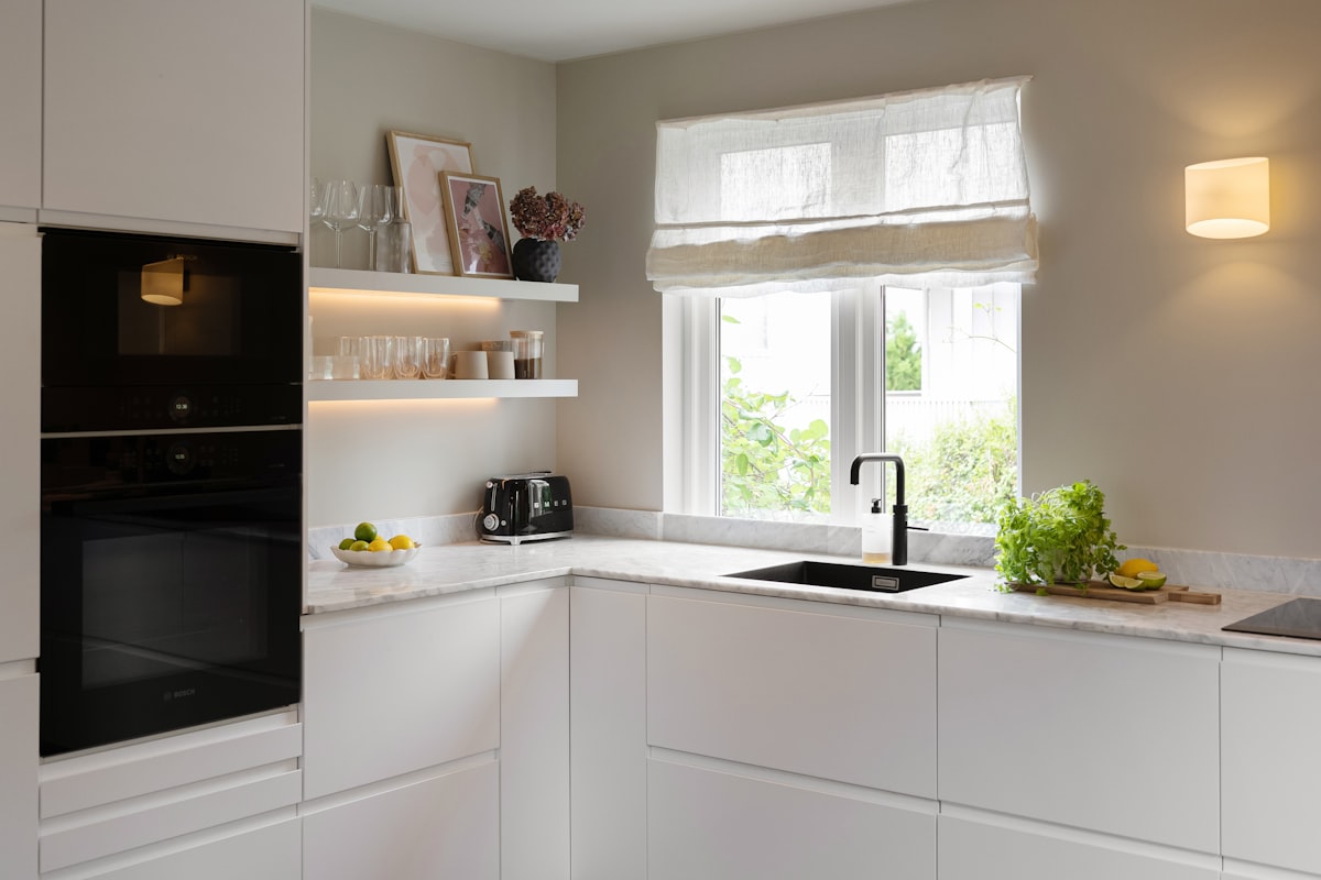 A kitchen with white cabinets and a black oven related to 10 Creative Kitchen Swags and Valances to Brighten Up Your Space