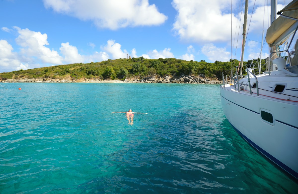 A lady floats beside a boat in turquoise blue sea water. related to Discover Top Home Essentials in Anchorage