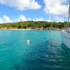 A lady floats beside a boat in turquoise blue sea water. related to Discover Top Home Essentials in Anchorage