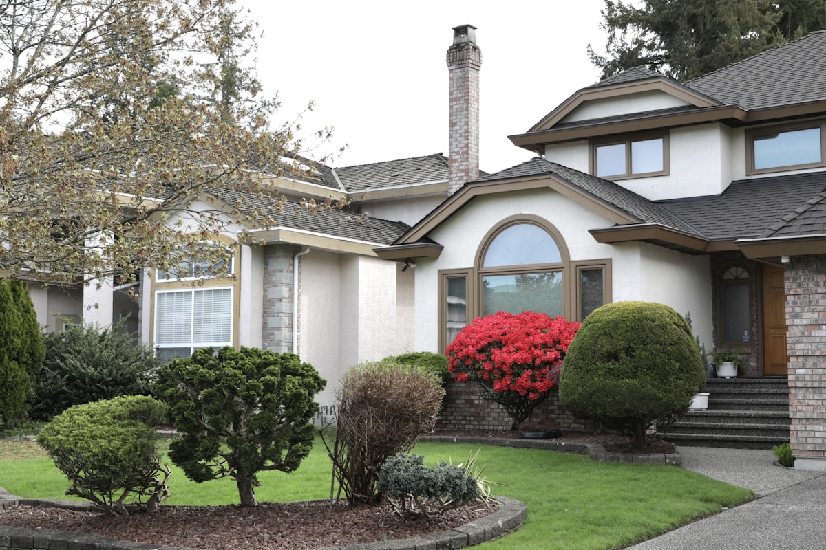 A large house with manicured bushes and red flowers. related to Boost Your Curb Appeal: The Ultimate Guide to Choosing Colors for Entryways
