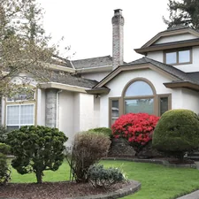 A large house with manicured bushes and red flowers. related to Boost Your Curb Appeal: The Ultimate Guide to Choosing Colors for Entryways