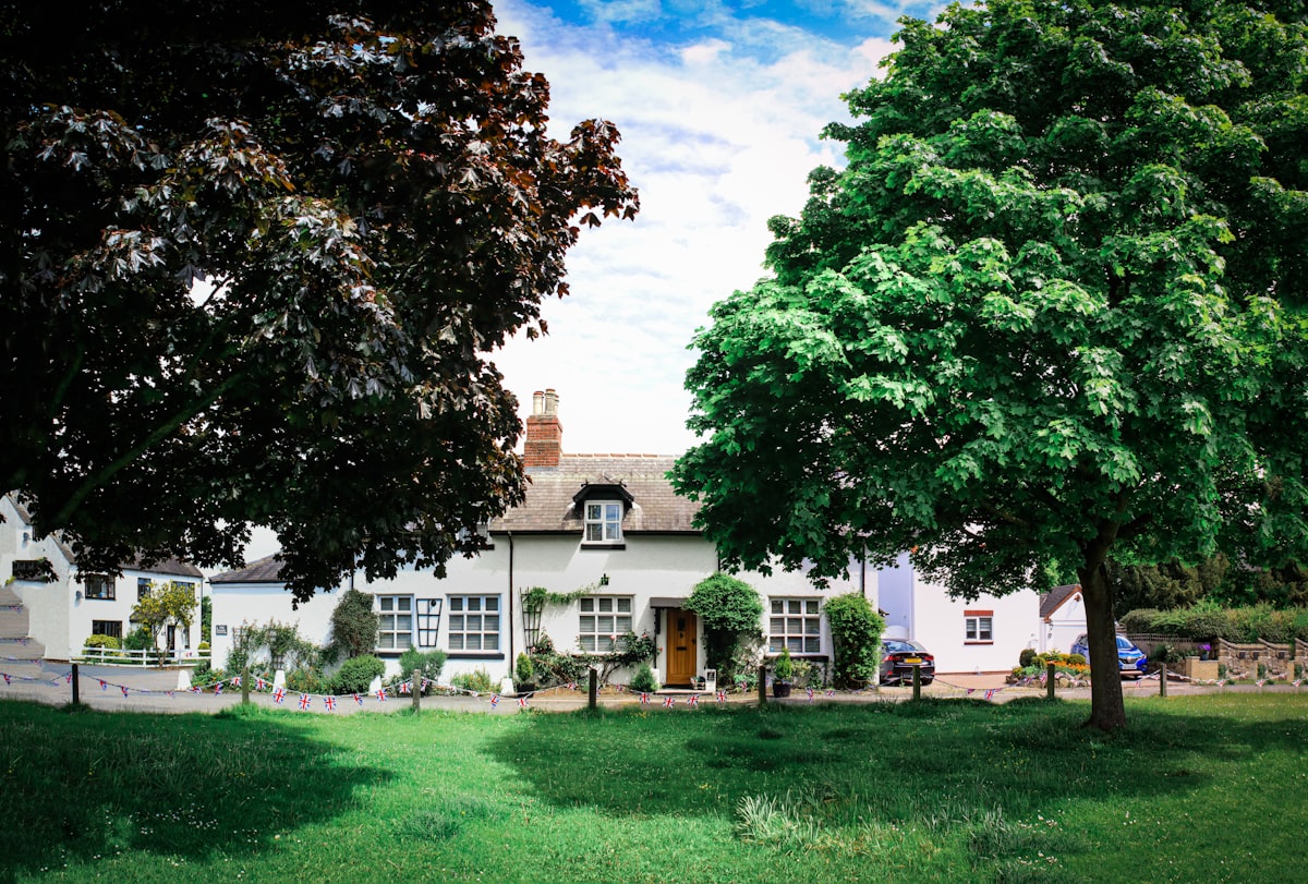 a large white house sitting next to a lush green field related to Discover the Charm of Twelve Oaks Bed and Breakfast