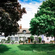 a large white house sitting next to a lush green field related to Discover the Charm of Twelve Oaks Bed and Breakfast