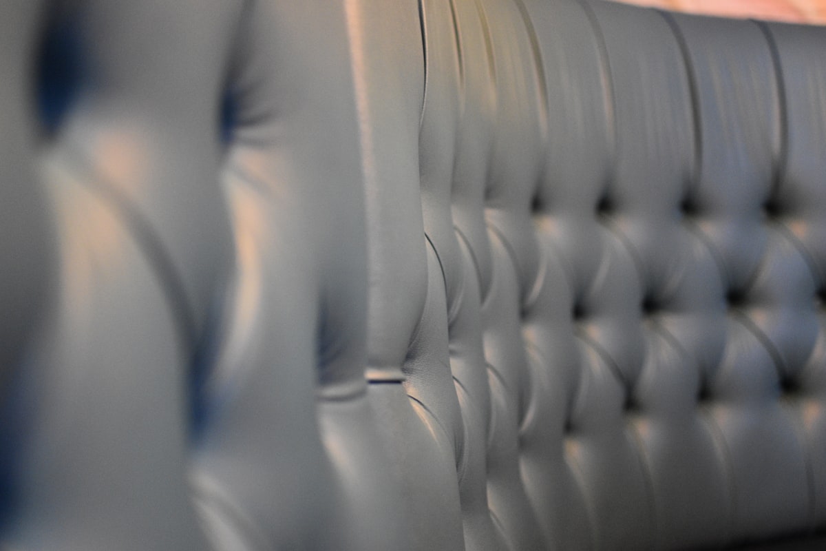 A leather couch back has detailed button tufting. related to Quilted Bed Valance: A Comprehensive Guide