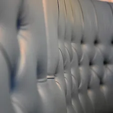 A leather couch back has detailed button tufting. related to Quilted Bed Valance: A Comprehensive Guide