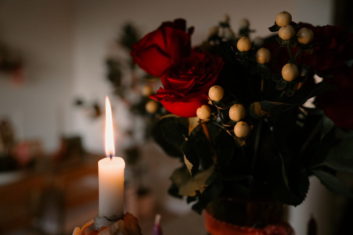 A lit candle beside a bouquet of red roses. related to Embracing Cozy Elegance: The Best Red Coverlet Queen Options