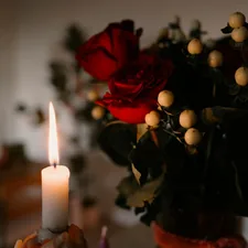 A lit candle beside a bouquet of red roses. related to Embracing Cozy Elegance: The Best Red Coverlet Queen Options