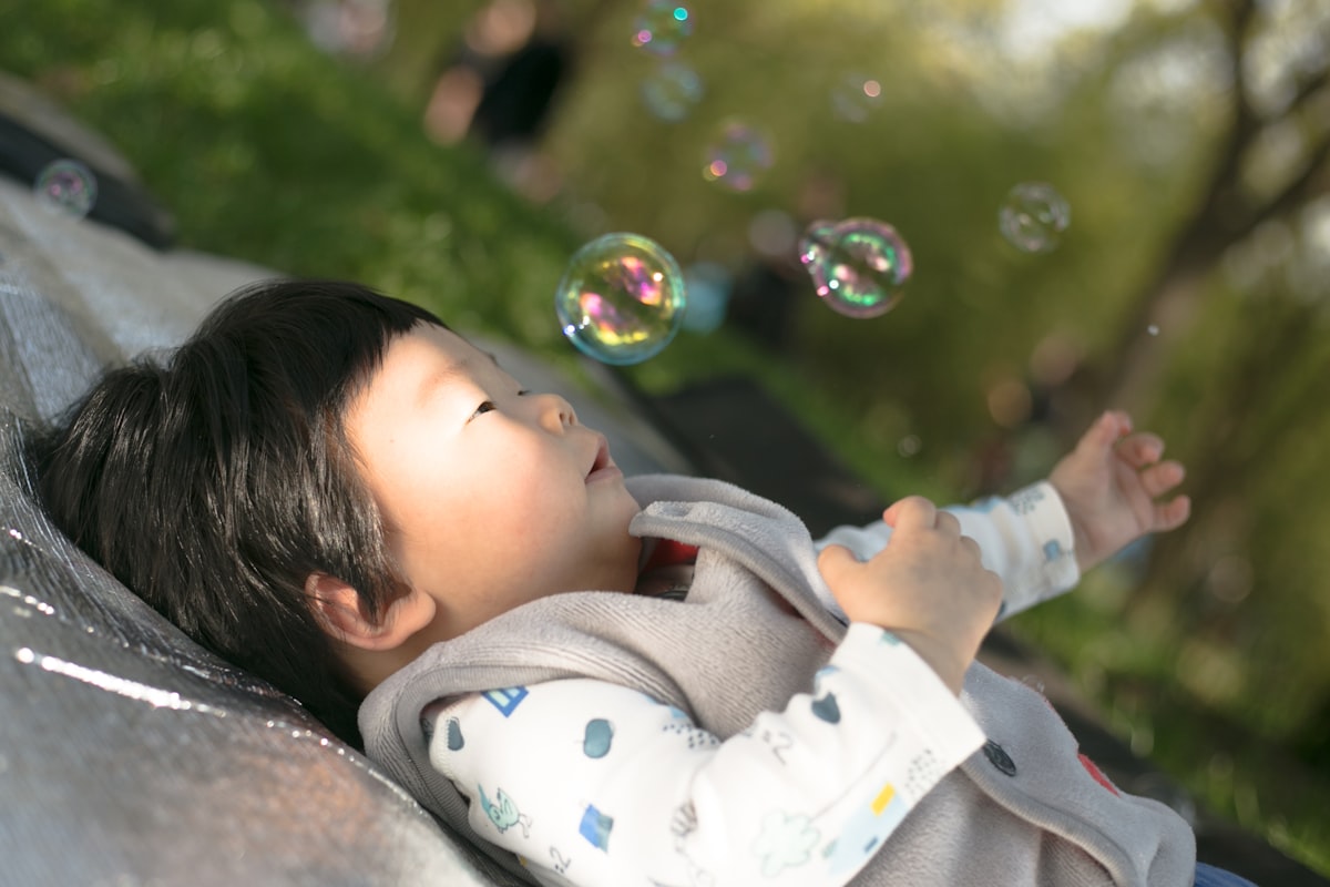 a little boy laying on top of a blanket next to bubbles related to Magical Dreams Await with a Toddler Bed Mickey Mouse