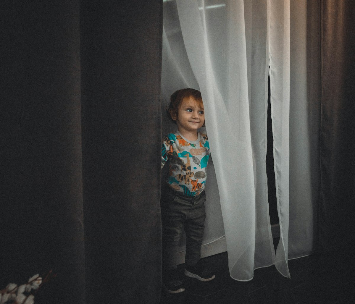 a little boy standing in front of a curtain related to Kids Curtain Valance: Elegant Window Treatments