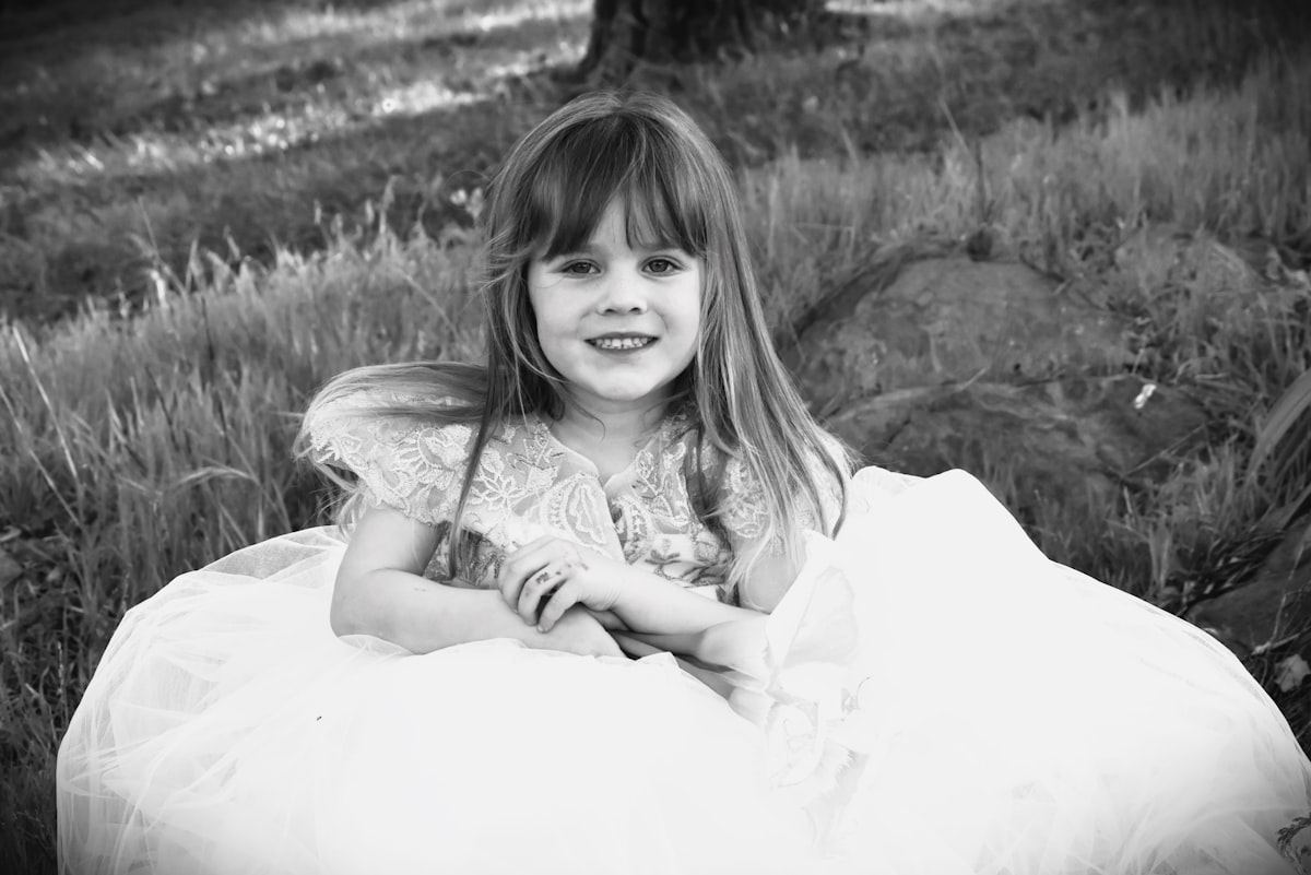 a little girl in a dress sitting in a field related to Girls Bed in a Bag: The Viral Trend Taking the Internet by Storm