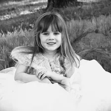 a little girl in a dress sitting in a field related to Girls Bed in a Bag: The Viral Trend Taking the Internet by Storm