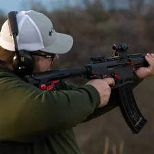 a man holding a rifle and wearing a hat related to Maximizing Your F250 Short Bed: A Complete Guide