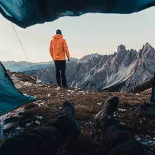 a man in an orange jacket standing in front of a tent related to Revolutionizing Your Outdoors: Outdoor Sideboards and Buffets