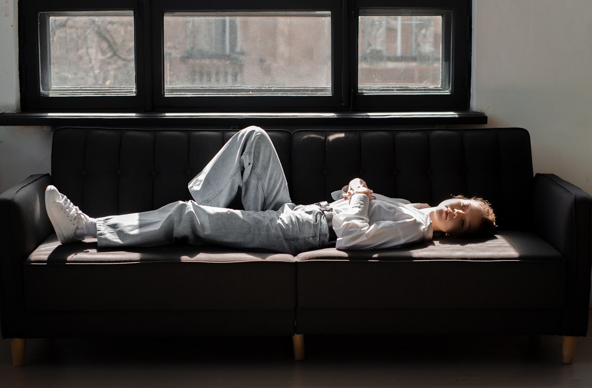 a man laying on top of a couch next to a window related to The Ultimate Sleeping Solution: Lazy Boy Sofa Bed