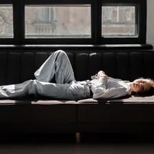 a man laying on top of a couch next to a window related to The Ultimate Sleeping Solution: Lazy Boy Sofa Bed