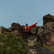 a man sitting on top of a large rock related to Elevate Your Outdoor Experience with a Hanging Bed