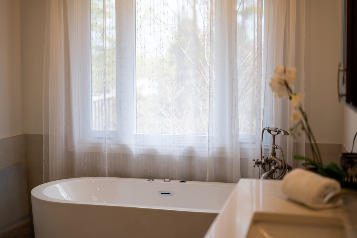 A modern bathtub with sheer curtains and a sink. related to Double Shower Curtains with Valance