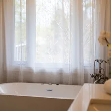 A modern bathtub with sheer curtains and a sink. related to Double Shower Curtains with Valance