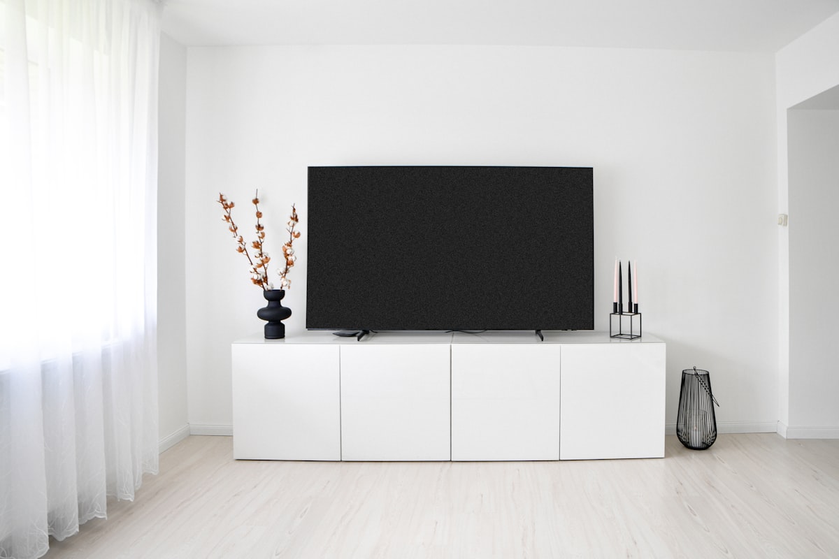 A modern minimalist living room interior featuring a large flat-screen television on a sleek white media console cabinet against a clean white wall.📸 Photo by me IG: @margoevardson related to Elevate Your Living Room Style with a White TV Sideboard