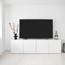 A modern minimalist living room interior featuring a large flat-screen television on a sleek white media console cabinet against a clean white wall.📸 Photo by me IG: @margoevardson related to Elevate Your Living Room Style with a White TV Sideboard