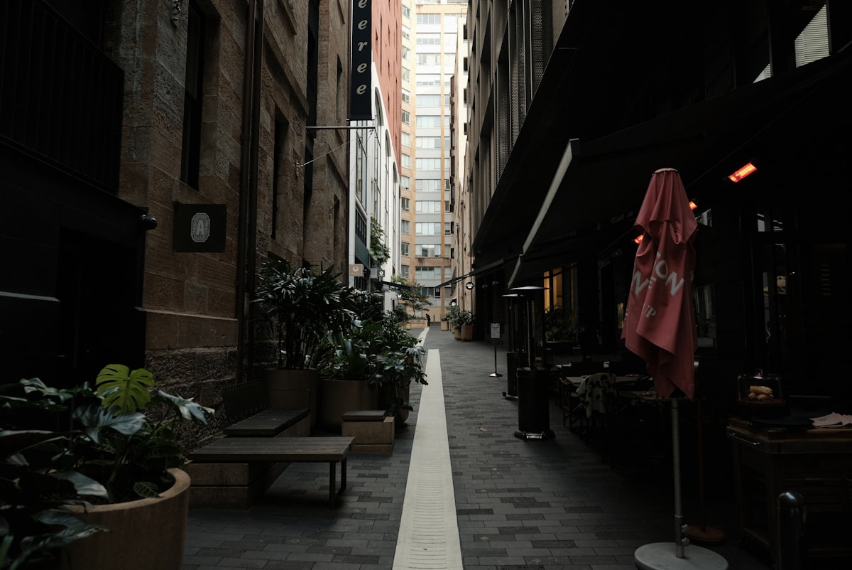 A narrow city street with tables and umbrellas related to Luxurious Peacock Alley Coverlets for Your Home Decor