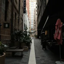 A narrow city street with tables and umbrellas related to Luxurious Peacock Alley Coverlets for Your Home Decor