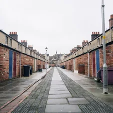 a narrow street with brick buildings on both sides related to Luxurious Peacock Alley Coverlets for Your Home Decor