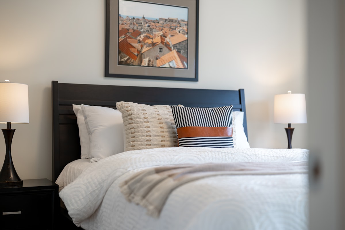 A neatly made bed with pillows and lamps. related to Contemporary Quilts and Coverlets