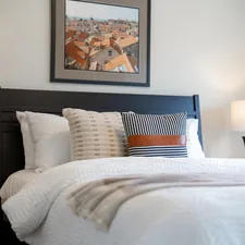 A neatly made bed with pillows and lamps. related to Contemporary Quilts and Coverlets