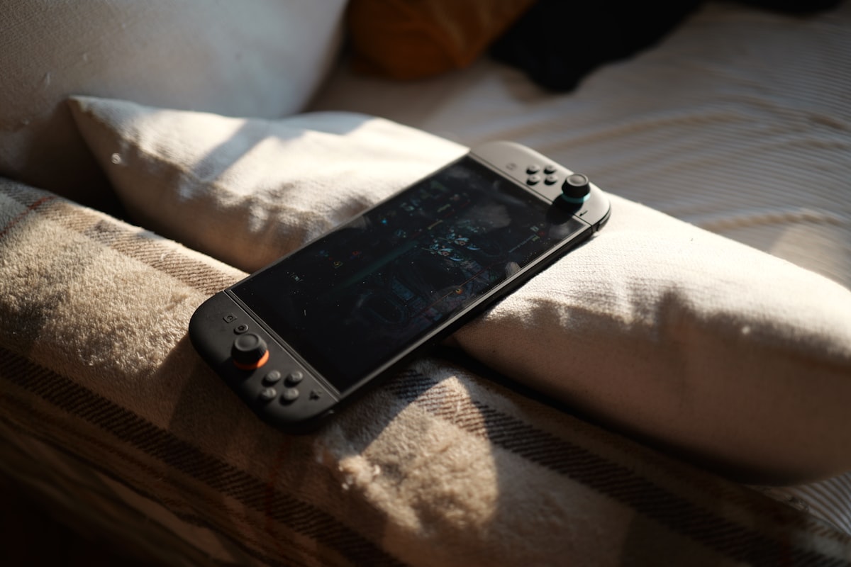 A nintendo switch rests on a comfy bed. related to Transform Your Bedroom with Fun Video Game Bedding