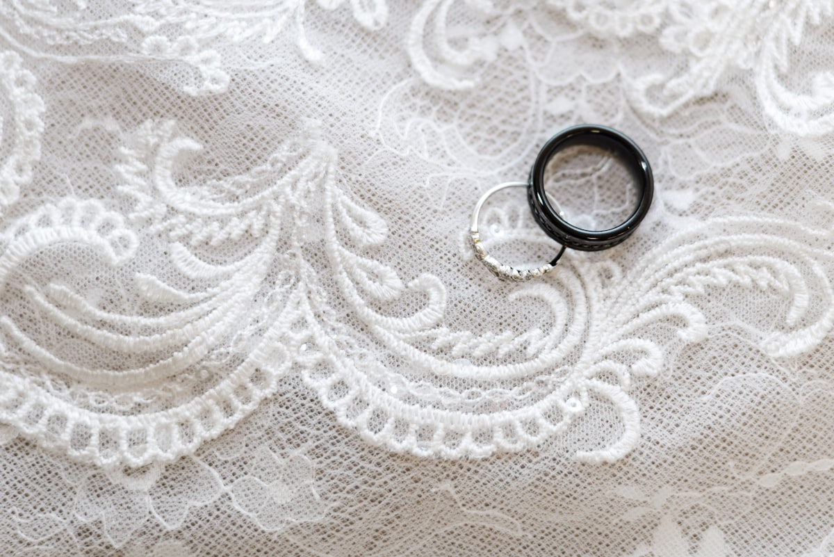 a pair of black rings sitting on top of a white lace related to Unveiling the Elegance of White Grommet Valance