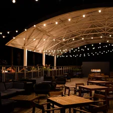 a patio with tables and chairs under a canopy related to Ignite the Night with La Hacienda's Timeless Cast Iron Chiminea