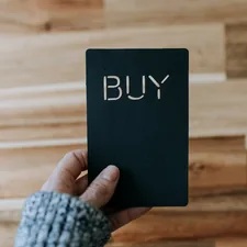a person holding a black book with the word buy written on it related to Where to Buy Valances