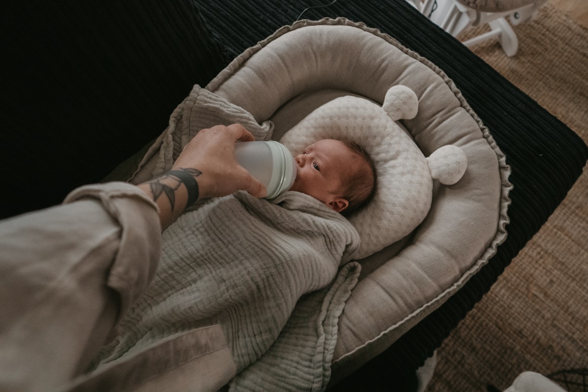 a person holding a bottle in their hand while holding a baby related to The Ultimate Guide to Gray Baby Beds
