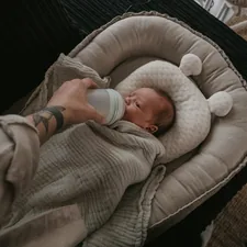 a person holding a bottle in their hand while holding a baby related to The Ultimate Guide to Gray Baby Beds