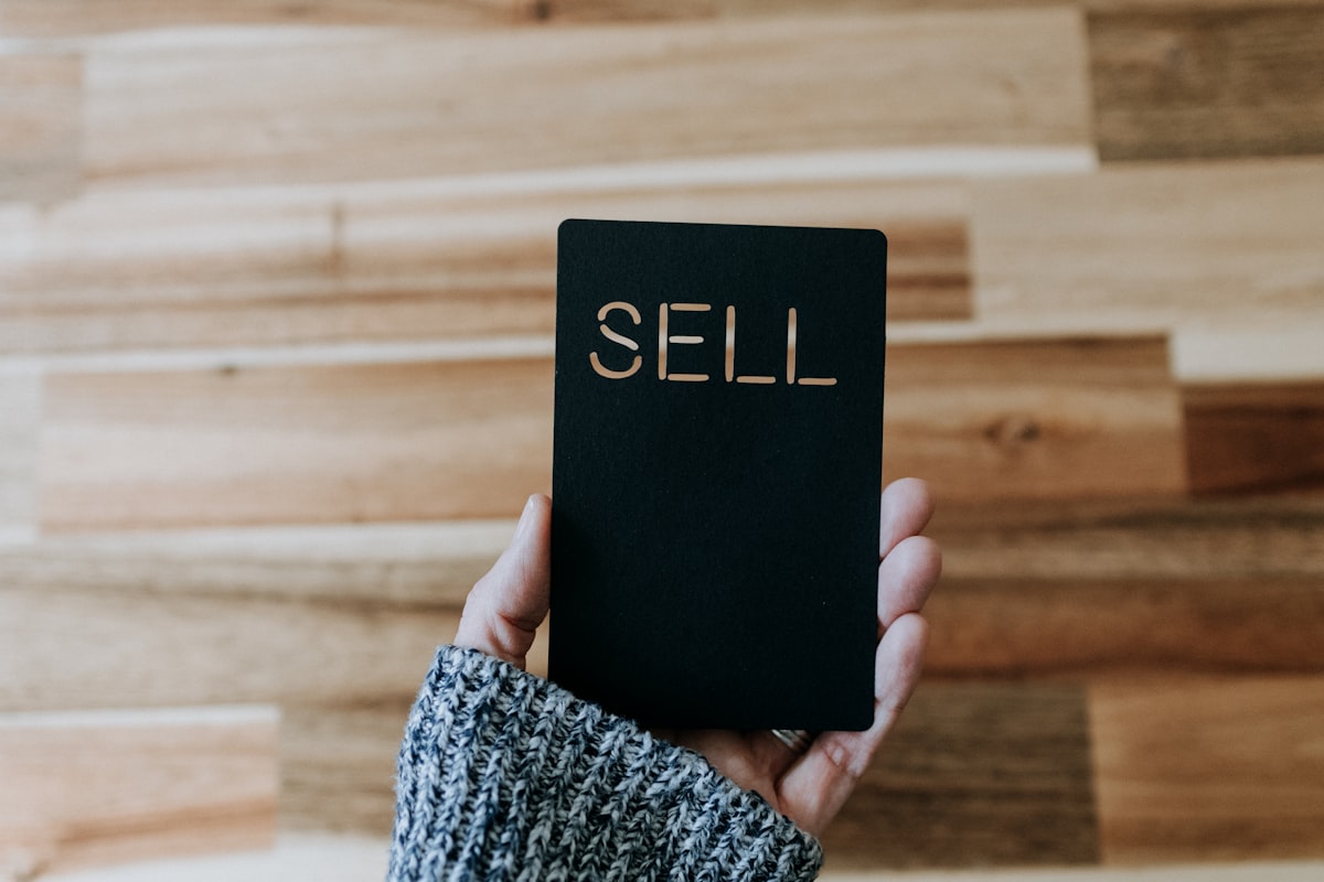 a person holding up a black book with the word sell written on it related to Ultimate Guide to Buying a Sofa Bed on Craigslist