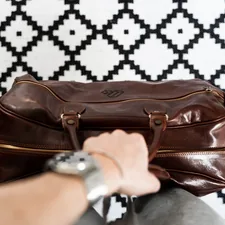 a person is holding a brown leather bag related to Elevate Your Home's Style with a Leather Entryway Bench