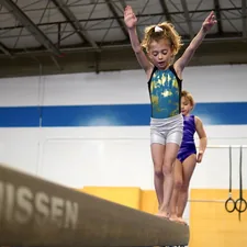 a person jumping on a trampoline with a child in the background related to Transform Your Child's Room with Gymnastics Bedding Sets