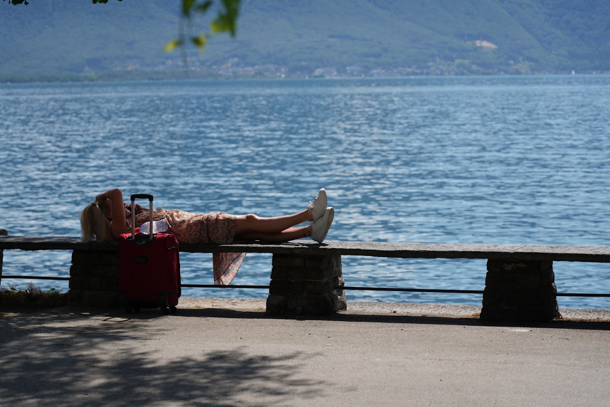 A person laying on a bench next to a body of water related to Charming Escapes at Bed and Breakfasts in Lake Geneva, WI