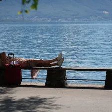 A person laying on a bench next to a body of water related to Charming Escapes at Bed and Breakfasts in Lake Geneva, WI