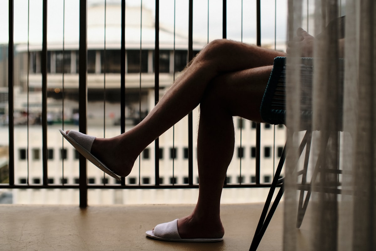 a person sitting on a chair with their legs crossed related to Understanding Leg Pain at Night in Bed