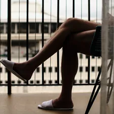 a person sitting on a chair with their legs crossed related to Understanding Leg Pain at Night in Bed