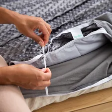 a person tying a pair of shoes with a pair of scissors related to What is a Bed Coverlet?
